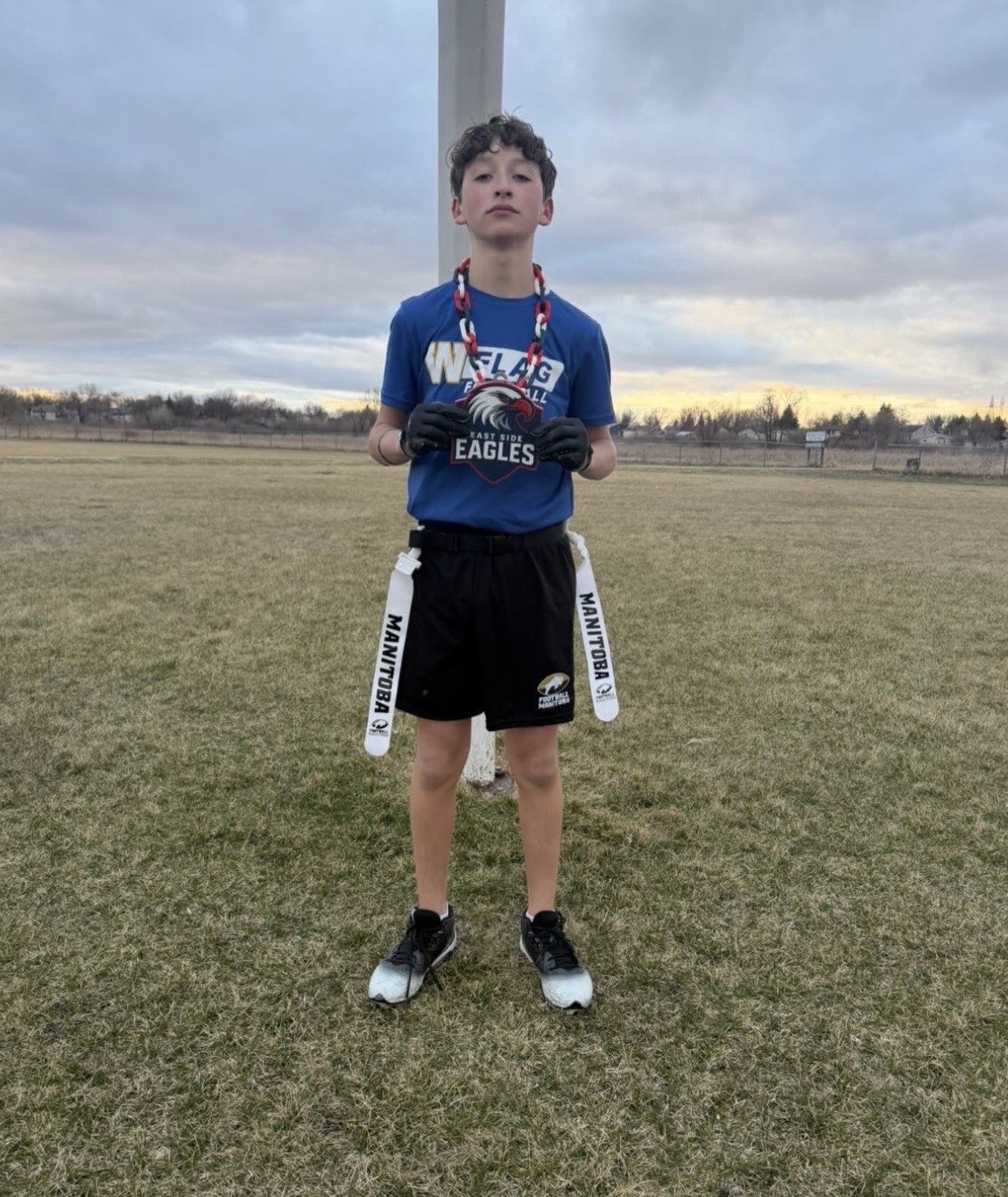 Eagles player holding the East Side Eagles medal on the outdoor field